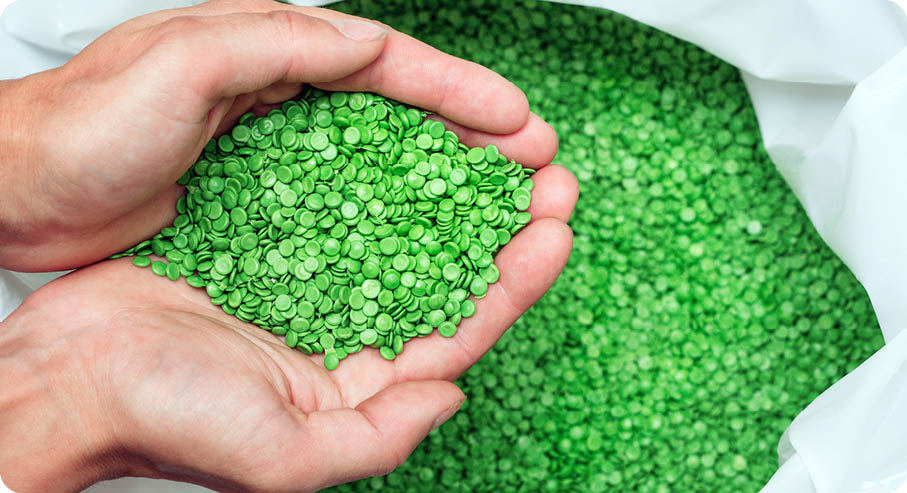 A hands hold or touching biodegradable plastic pellets, plastic polymer dye granules color clear green 